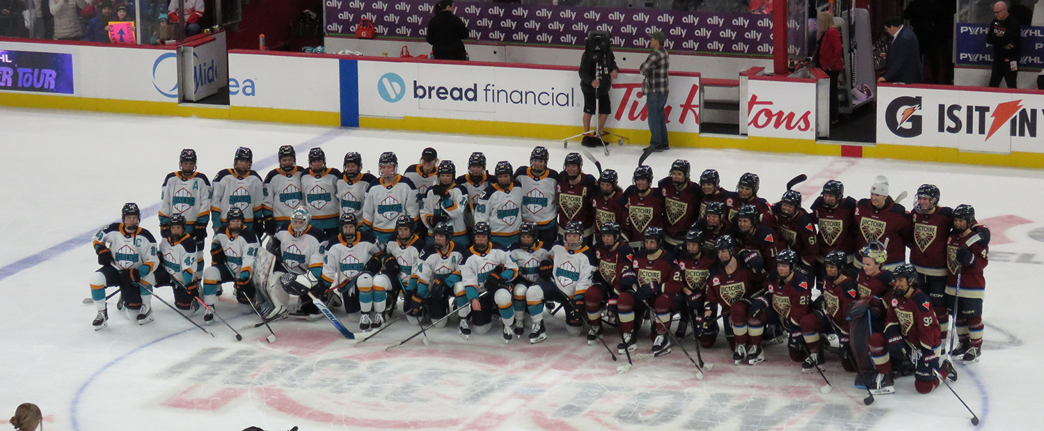 The New York Sirens and Montreal Victoire pose at center ice for a group photo after the PWHL Takeover Tour Detroit game.