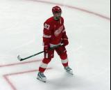 Alex DeBrincat of the Detroit Red Wings stands in a faceoff circle during pre-game warmups before a game against the Carolina Hurricanes, wearing a customized Sergei Fedorov jersey and white skates in honor of Fedorov's jersey retirement.