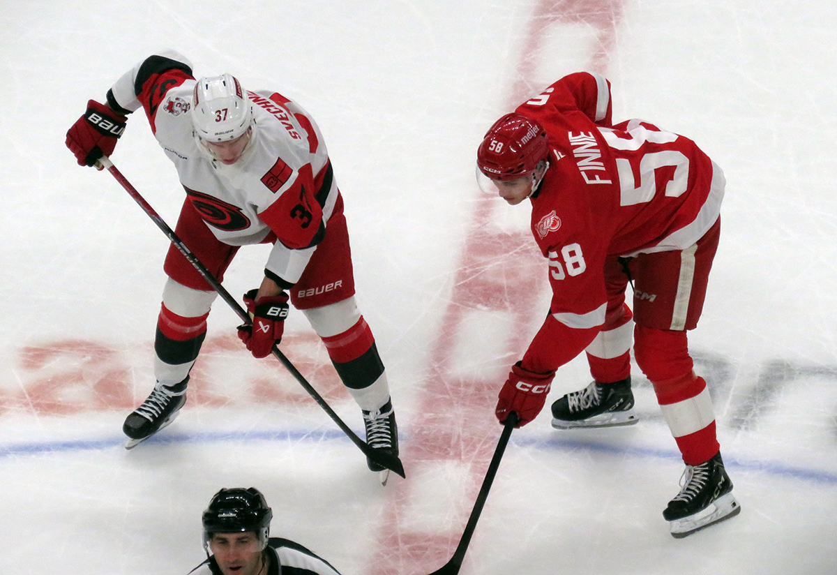 Andrei Svechnikov of the Carolina Hurricanes and Emmitt Finnie of the Detroit Red Wings line up at wing for a faceoff.