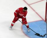 Dylan Larkin of the Detroit Red Wings clears pucks from the crease during pre-game warmups before a game against the Carolina Hurricanes, wearing a customized Sergei Fedorov jersey and white skates in honor of Fedorov's jersey retirement.