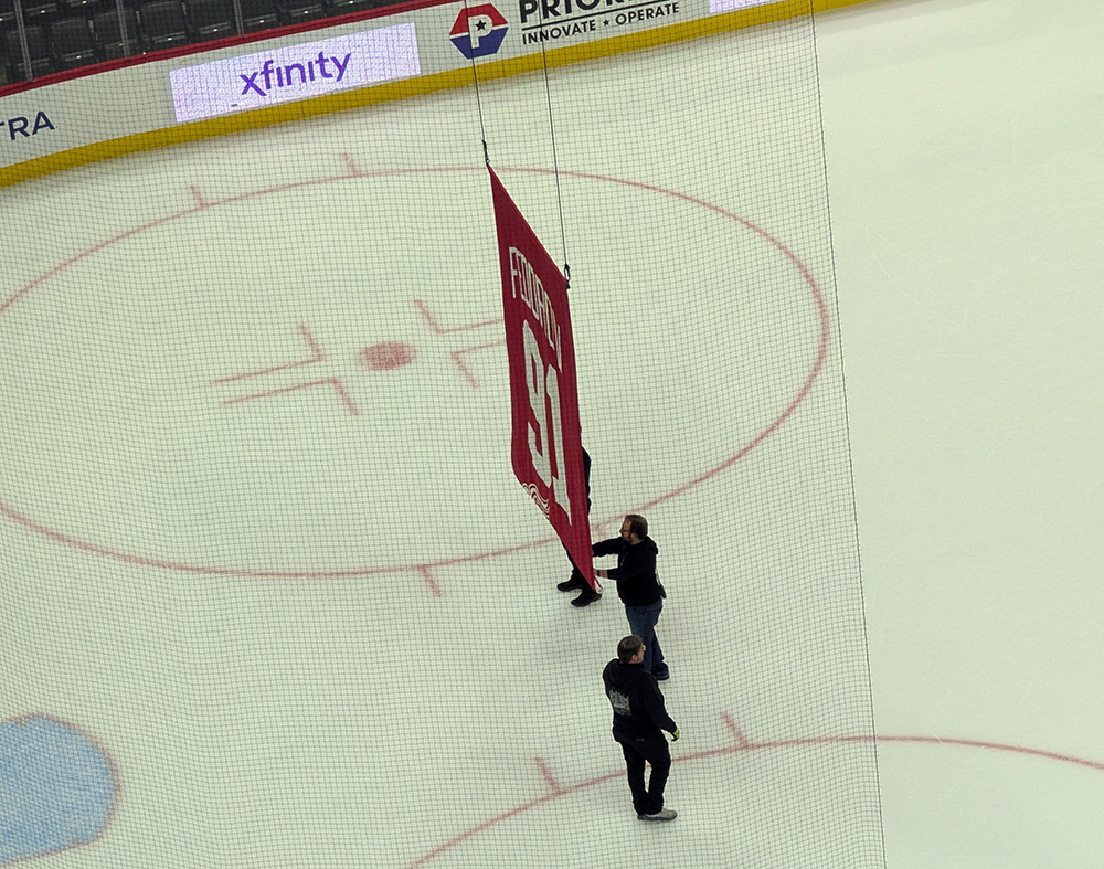 Workers remove Sergei Fedorov's retired number banner from the Little Caesars Arena rafters after Fedorov's jersey retirement game.