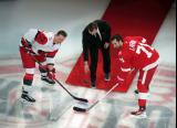 Andrei Svechnikov of the Carolina Hurricanes and Dylan Larkin of the Detroit Red Wings take a ceremonial faceoff from Sergei Fedorov as part of Fedorov's jersey retirement ceremony.