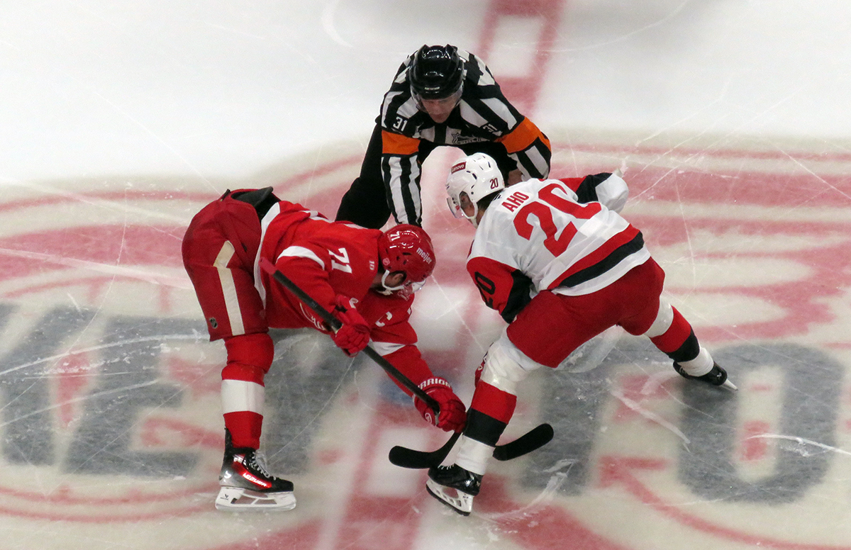 Dylan Larkin of the Detroit Red Wings takes a faceoff against Sebastian Aho of the Carolina Hurricanes.
