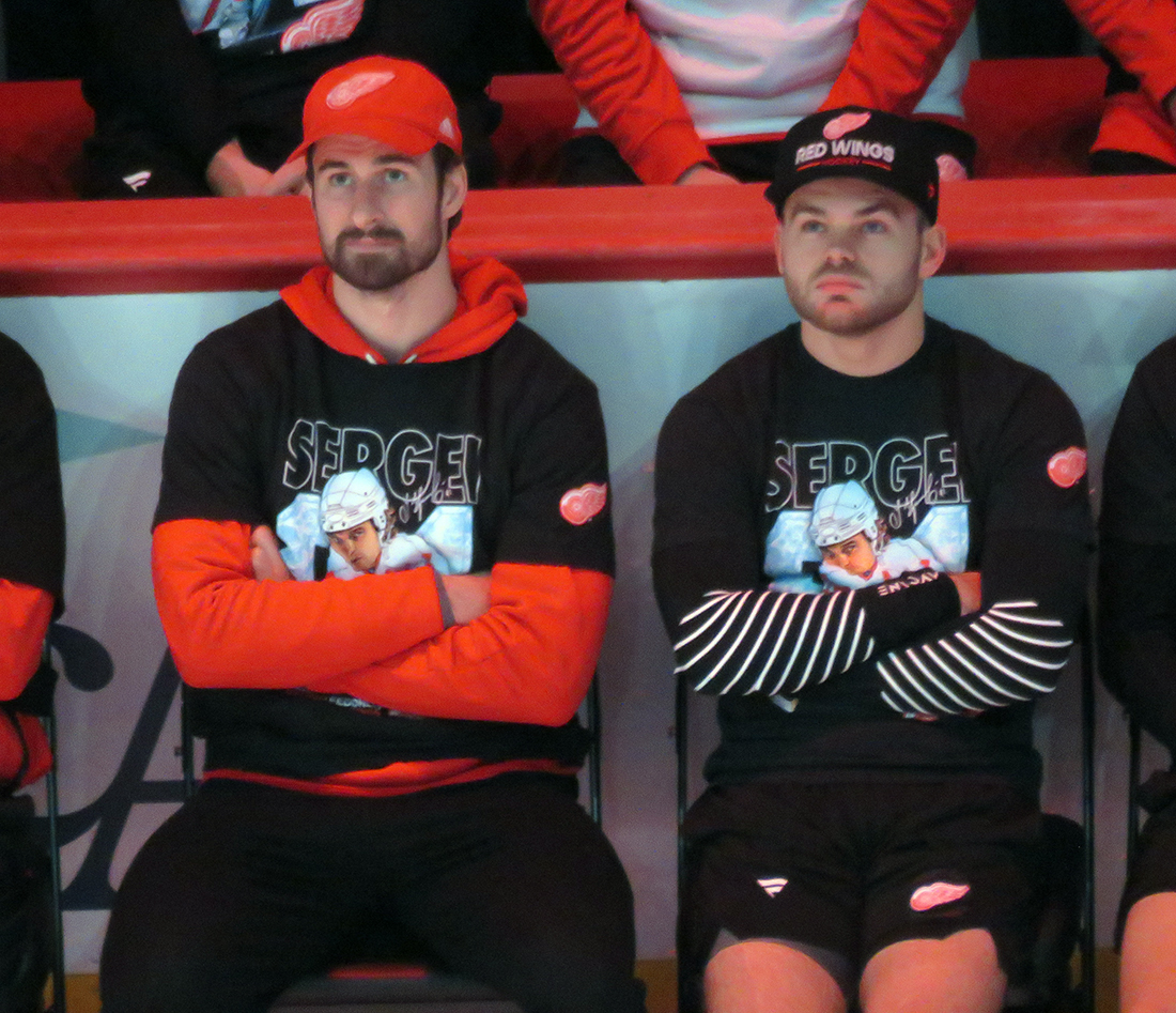 Dylan Larkin and Alex DeBrincat watch Sergei Fedorov speak during Fedorov's jersey retirement ceremony.