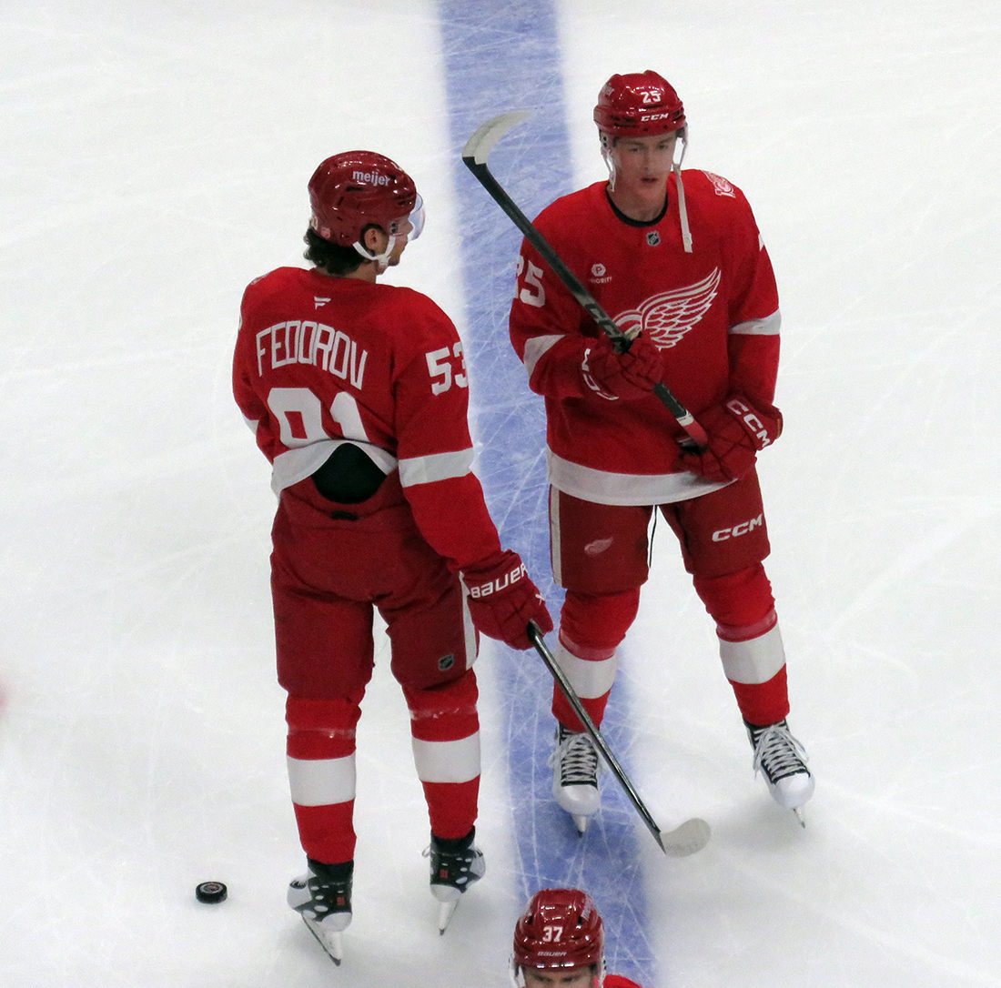 Moritz Seider and Jacob Bernard-Docker of the Detroit Red Wings stand at the blue line during pre-game warmups before a game against the Carolina Hurricanes, wearing customized Sergei Fedorov jerseys and white skates in honor of Fedorov's jersey retirement.