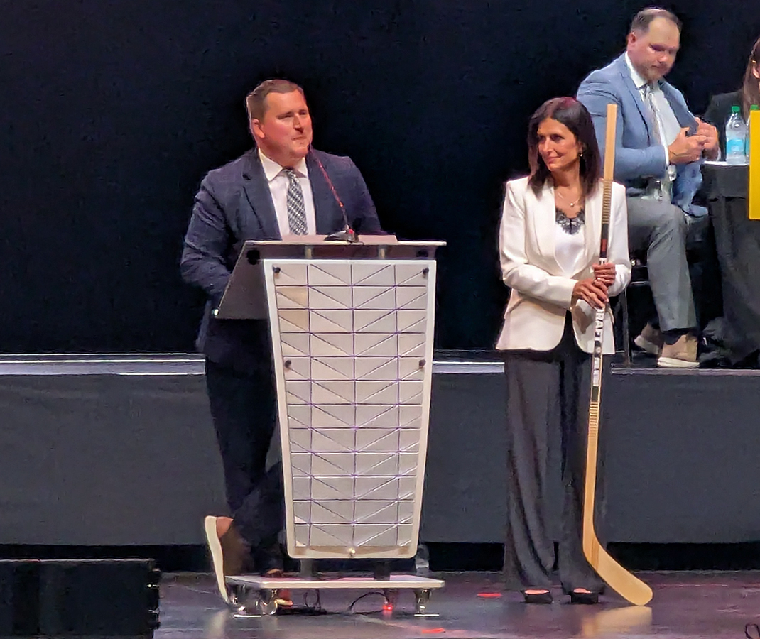 PWHL Detroit head coach Josh Sciba steps to the podium alongside general manager Manon Rheaume to announce the team's sixth-round pick in the 2026 PWHL Entry Draft.